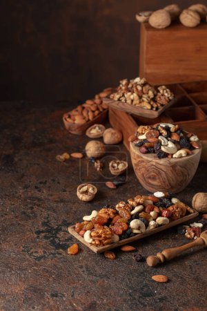 Photo for Mix of nuts and raisins on a brown rustic background. Presented raisins, walnuts, hazelnuts, cashews, pecans, and almonds. - Royalty Free Image