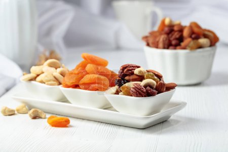 Téléchargez les photos : Fruits secs et noix assorties sur une table en bois blanc. - en image libre de droit