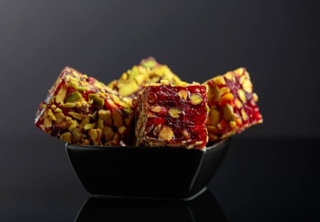 Photo for Traditional Turkish delight in a small black dish on a black reflective background. - Royalty Free Image