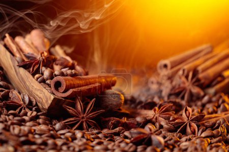 Foto de Roasted coffee beans with cinnamon sticks, anise, and nutmeg. Steaming coffee beans with spices in a wooden dish. - Imagen libre de derechos