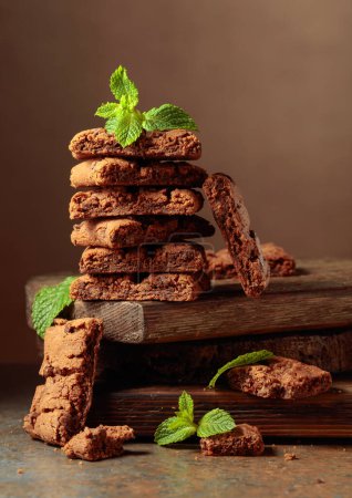 Téléchargez les photos : Pieces of fresh brownie with mint on a rustic brown background. - en image libre de droit