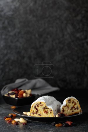 Foto de Traditional fruit cake with raisins and nuts on a black table. Copy space. - Imagen libre de derechos
