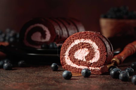 Photo for Chocolate roll cake with blueberries on a an old brown table. - Royalty Free Image