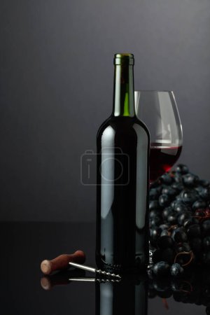 Téléchargez les photos : Red wine and blue grapes on a black reflective background. - en image libre de droit