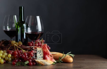 Photo for Sandwich with prosciutto, blue cheese and rosemary on a dark background. Delicious snack and red wine. - Royalty Free Image