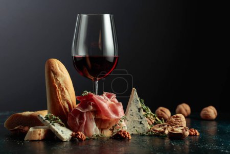 Photo for Prosciutto with blue cheese, red wine, baguette, walnuts, and thyme. Red wine with traditional Mediterranean snacks. - Royalty Free Image