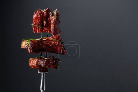 Téléchargez les photos : Grilled pork belly with rosemary on a fork. Copy space. - en image libre de droit