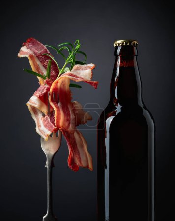 Photo for Unopened beer bottle and slices of fried bacon. - Royalty Free Image