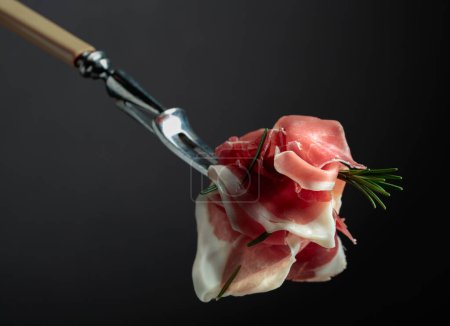 Téléchargez les photos : Sliced prosciutto with rosemary on a fork. - en image libre de droit