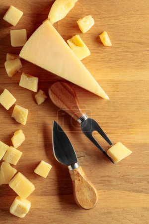 Foto de Parmesan cheese with fork and knife on a wooden background. Top view. - Imagen libre de derechos