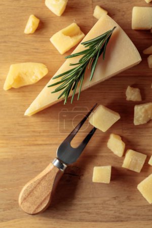 Foto de Parmesan cheese with rosemary on a wooden background. Top view. - Imagen libre de derechos