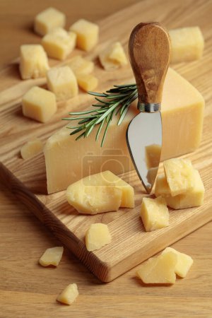 Foto de Parmesan cheese with rosemary and knife on a wooden cutting board. - Imagen libre de derechos