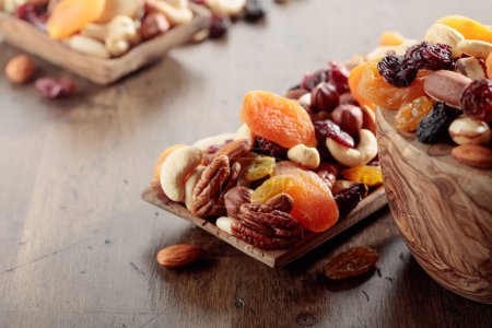 Foto de Mix of nuts and dried fruits on an old wooden table. Presented apricots, raisins, walnuts, hazelnuts, cashews, pecans, and almonds. Selective focus. - Imagen libre de derechos