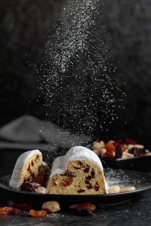 Téléchargez les photos : Gâteau aux fruits traditionnel aux raisins secs et aux noix saupoudré de sucre en poudre. - en image libre de droit