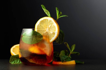 Téléchargez les photos : Cocktail d'été froid et rafraîchissant Cuba libre avec tranches de citron et menthe sur fond noir. Espace de copie. - en image libre de droit