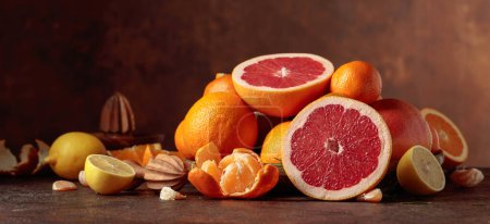 Téléchargez les photos : Agrumes sur une vieille table brune. Les oranges, pamplemousses, citrons et mandarines sont présentés. - en image libre de droit