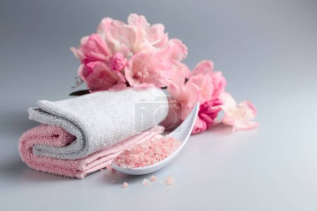 Photo for Spa composition with pink Himalayan salt, flowers, and towel. - Royalty Free Image