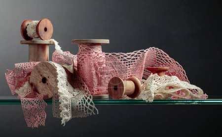 Téléchargez les photos : Vintage pink and beige cotton lace trims on wooden spools. - en image libre de droit