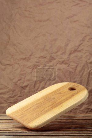 Photo for Cutting board falling on an old wooden table. Food preparation. Culinary background. Empty wooden cutting board, product display space. - Royalty Free Image