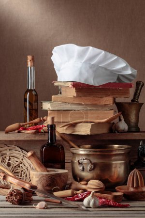 Photo for Chef's hat, vintage cookbooks, and old kitchen utensils on a wooden table. A conceptual image on the theme of culinary art. Selective focus. - Royalty Free Image