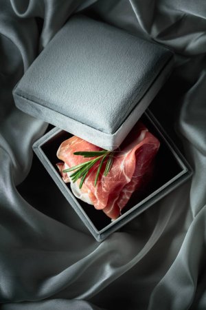 Photo for Prosciutto with rosemary in a gray gift box. Concept of the theme of expensive food. - Royalty Free Image