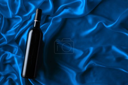 Photo for Bottle of red wine on a blue satin background. Top view. - Royalty Free Image