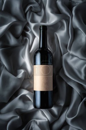 Téléchargez les photos : Bottle of red wine with an empty label on a grey satin background. Top view. - en image libre de droit