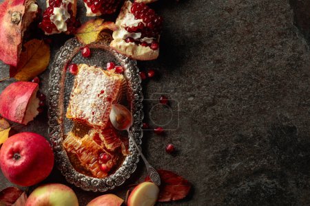 Foto de Apple, pomegranate, and honey, are the traditional food for Jewish New Year - Rosh Hashana. Honeycomb and fruits on an old stone table. Copy space. - Imagen libre de derechos