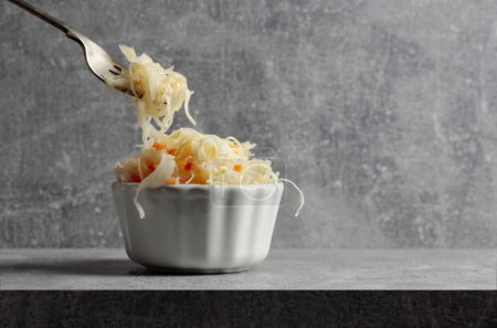 Photo for Bowl of sauerkraut with a carrot on a grey stone table. - Royalty Free Image