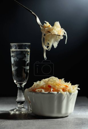 Téléchargez les photos : Bowl of sauerkraut and a glass of vodka on a grey stone table. - en image libre de droit