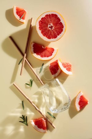 Téléchargez les photos : Grapefruit slices, rosemary, straws, and an empty glass. Top view. - en image libre de droit