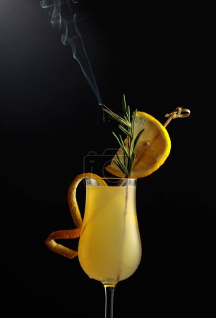 Foto de Limoncello en un vaso. Un licor de limón italiano dulce, una bebida alcohólica fuerte tradicional adornada con una rama de romero humeante. - Imagen libre de derechos