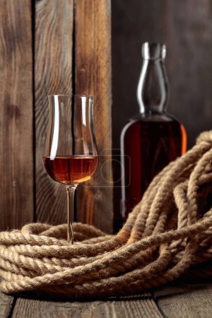 Téléchargez les photos : Snifter et bouteille avec rhum, cognac ou whisky sur un vieux fond en bois. - en image libre de droit