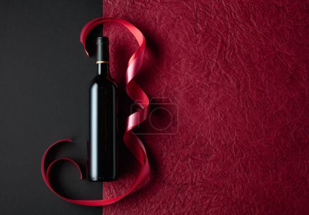 Téléchargez les photos : Bottle of red wine with red and pink satin ribbons. Top view. - en image libre de droit