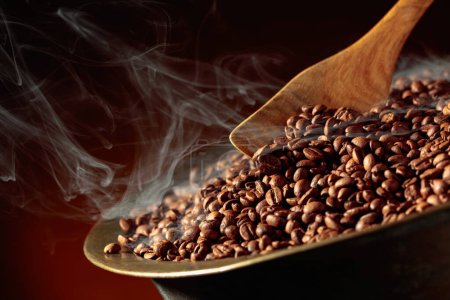 Téléchargez les photos : Les grains de café moyennement torréfiés sont fumés dans une rôtissoire. Espace de copie. - en image libre de droit