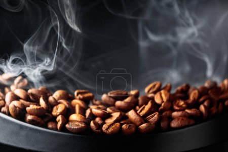 Photo for Steaming coffee beans on a black background. Selective focus. Copy space. - Royalty Free Image