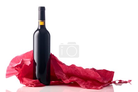 Téléchargez les photos : Bouteille de vin rouge avec papier crêpe rouge froissé isolé sur fond blanc. - en image libre de droit