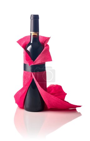 Foto de Botella de vino tinto envuelta en papel crepé aislado sobre un fondo blanco. La botella parece una mujer con un vestido de noche rojo. - Imagen libre de derechos