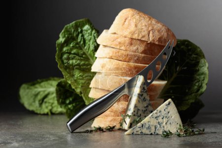 Foto de Rebanadas de queso azul con pan, lechuga, tomillo y cuchillo de queso. - Imagen libre de derechos