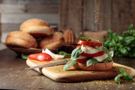 Téléchargez les photos : Sandwich à la mozzarella, tomates et basilic saupoudré d'épices. - en image libre de droit