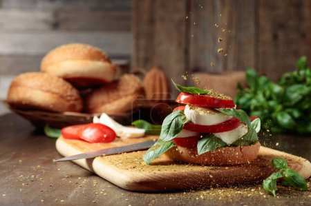 Téléchargez les photos : Sandwich à la mozzarella, tomates et basilic saupoudré d'épices. - en image libre de droit