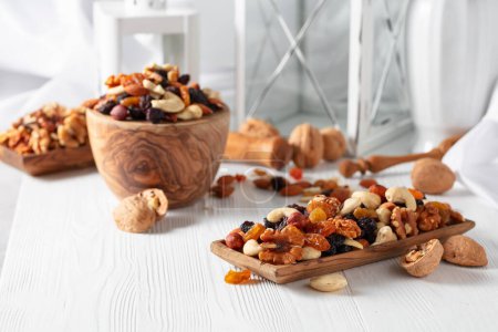 Photo for Mix of nuts and raisins on a white wooden table. Presented raisins, walnuts, hazelnuts, cashews, pecans, and almonds. - Royalty Free Image