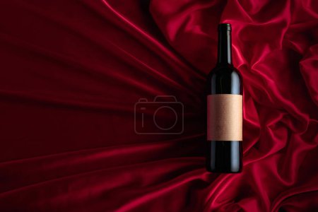 Photo for Bottle of red wine with an empty label on a satin background. Top view. - Royalty Free Image