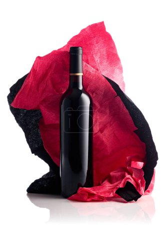 Téléchargez les photos : Bottle of red wine with crumpled red and black crepe paper isolated on a white background. - en image libre de droit