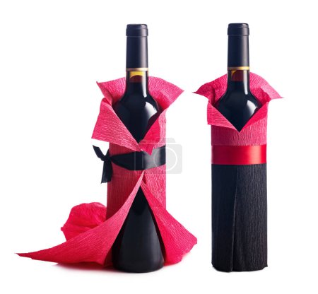 Photo for Bottles of red wine wrapped in crepe paper isolated on a white background. The bottles look like a man and a woman. - Royalty Free Image