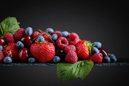 Photo for Berries closeup colorful assorted mix of strawberry, blueberry, raspberry and sweet cherry in studio on dark background. - Royalty Free Image