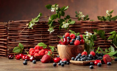 Photo for Berries closeup colorful assorted mix of strawberry, blueberry, raspberry and sweet cherry on a old wooden table in garden. Various juicy berries with leaves. - Royalty Free Image