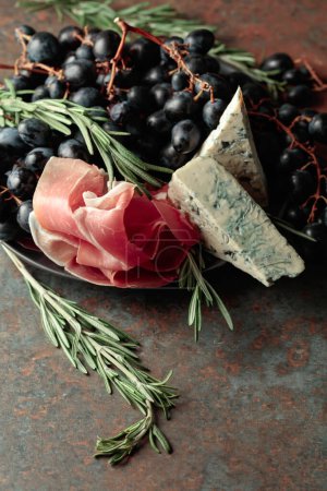 Foto de Prosciutto con queso azul, uvas y romero, sobre fondo vintage. - Imagen libre de derechos