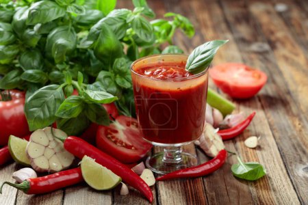 Photo for Homemade tomato sauce and ingredients. Fresh tomatoes, red peppers, garlic, basil, and lime on an old wooden table. - Royalty Free Image