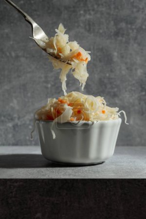 Photo for Bowl of sauerkraut with a carrot on a grey stone table. - Royalty Free Image